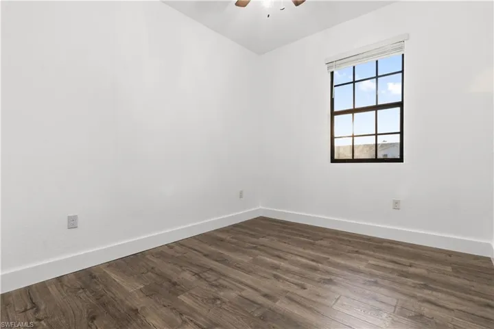 Unfurnished room featuring dark wood-style flooring and a ceiling fan