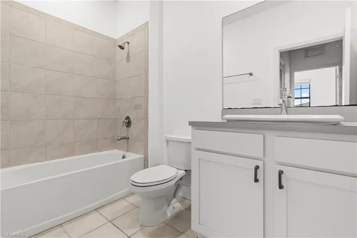 Bathroom featuring  shower combination, vanity, and light tile patterned flooring