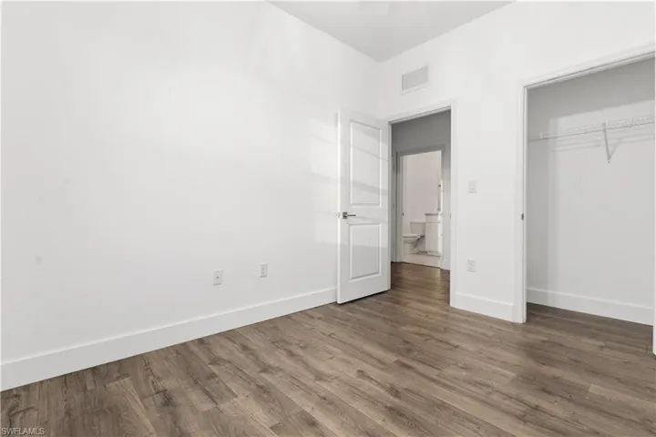 Unfurnished bedroom with dark wood-style flooring and a closet