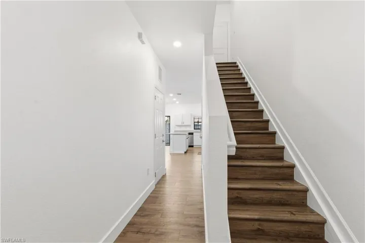Stairs with wood finished floors and recessed lighting
