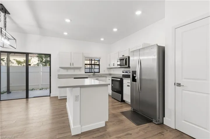 Kitchen featuring stainless steel appliances, light countertops, white cabinets, and dark wood-type flooring