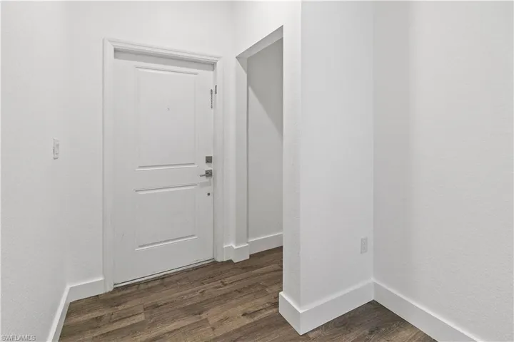 Entryway with dark wood-type flooring and a textured wall