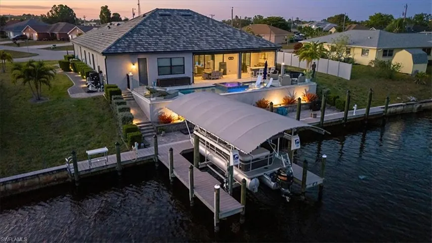 Back of house with boat lift, a fenced backyard, a water view, and a patio area