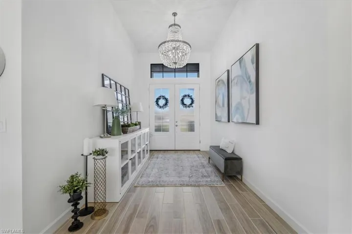 Entryway with wood tiled floors, a chandelier, french doors, and a towering ceiling