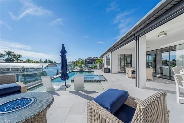 View of patio featuring a pool with connected hot tub, an outdoor living space with a fire pit, and outdoor dining area