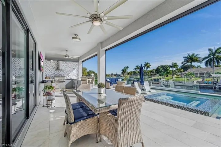 View of patio featuring area for grilling, outdoor dining area, ceiling fan, and a pool with connected hot tub