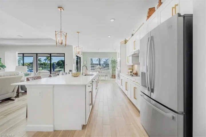 Kitchen with stainless steel refrigerator with ice dispenser, white cabinets, a spacious island, open floor plan, and light wood finished floors