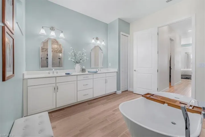Bathroom featuring double vanity, wood tiled floors, a soaking tub, and ensuite bath