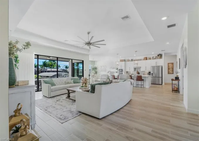 Living room featuring wood tiled floors, a tray ceiling, ceiling fan, and recessed lighting