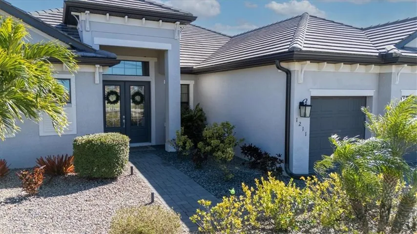 Doorway to property featuring a tiled roof, stucco siding, a garage, and french doors
