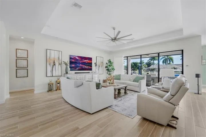 Living area with a tray ceiling, wood tiled floors, and a ceiling fan