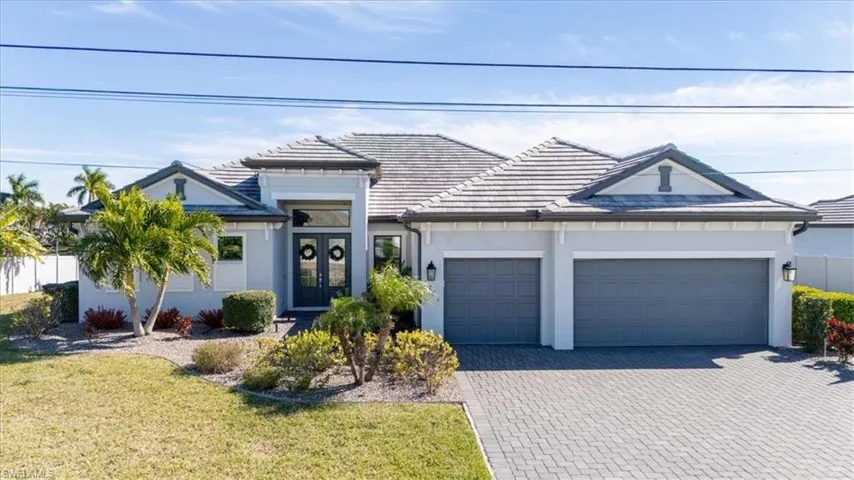 View of front of house featuring decorative driveway, stucco siding, a front yard, french doors, and an attached garage