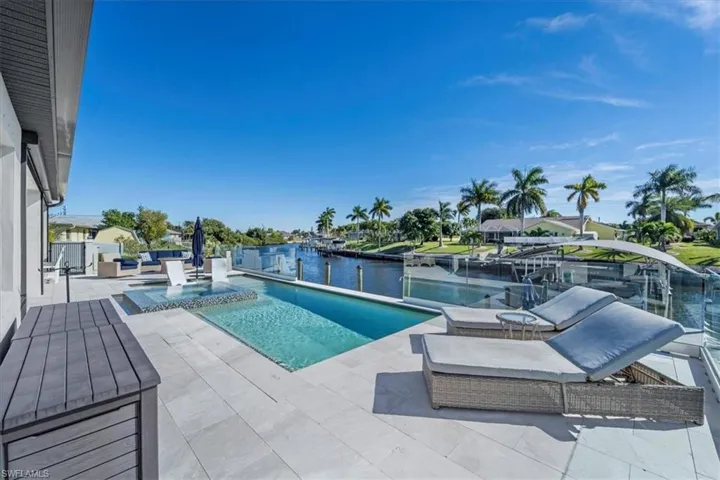 View of pool featuring an infinity pool, a patio area, a water view, and a boat dock