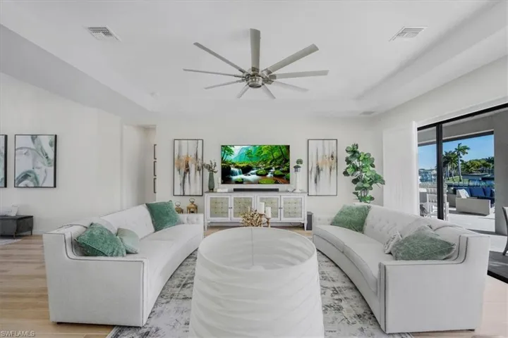 Living area featuring a tray ceiling, wood finished floors, and a ceiling fan