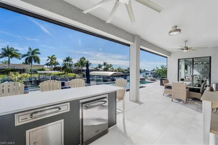 View of patio / terrace with ceiling fan, outdoor dining space, an outdoor kitchen, and an outdoor pool