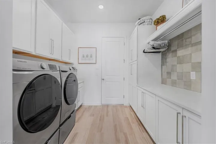 Laundry area featuring cabinet space, light wood-type flooring, and washing machine and clothes dryer