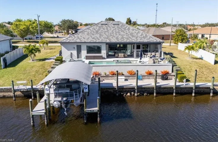 Dock with a fenced backyard, a patio area, boat lift, and a water view