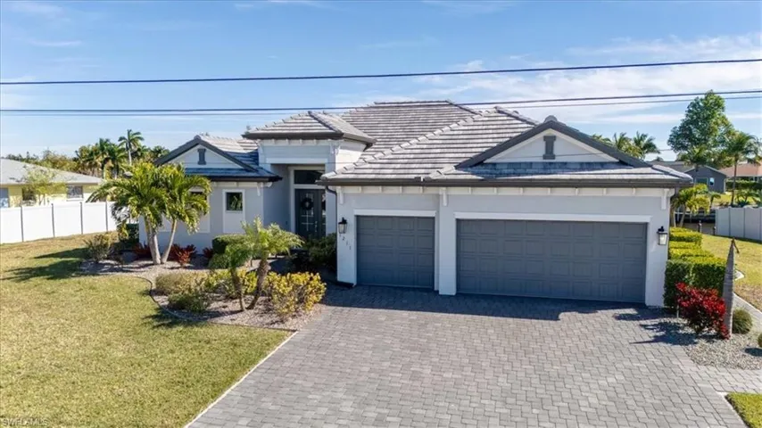 View of front facade with stucco siding, decorative driveway, an attached garage, and a tile roof
