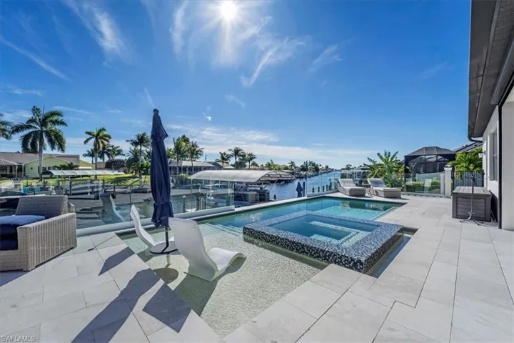 View of pool with a patio, a water view, a dock, a pool with connected hot tub, and boat lift