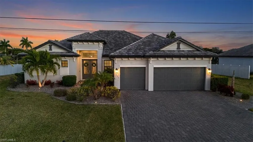 View of front of property featuring stucco siding, decorative driveway, and an attached garage