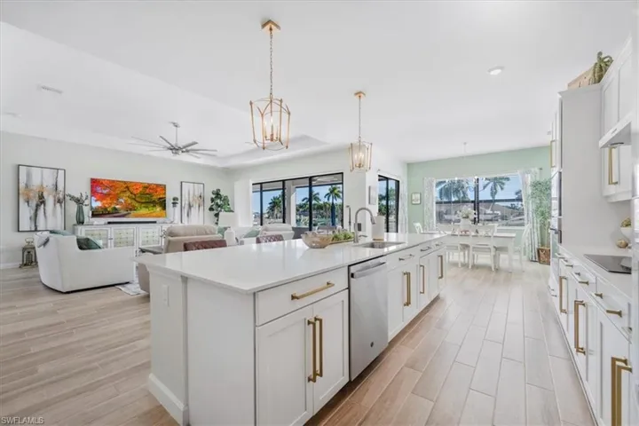 Kitchen with white cabinets, decorative light fixtures, open floor plan, and wood finish floors