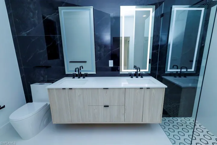 Full bathroom with tile walls, a sink, toilet, and a shower stall