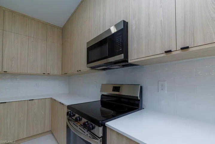 Kitchen featuring modern cabinets, light countertops, light brown cabinetry, and stainless steel appliances
