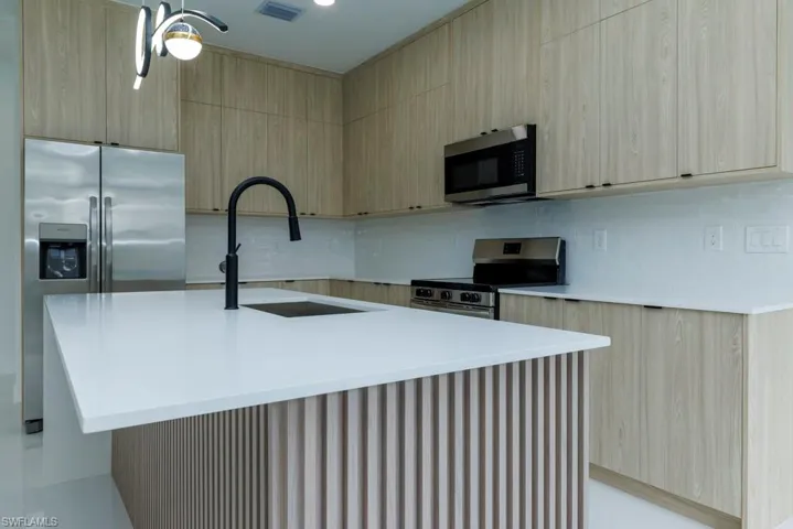 Kitchen featuring light countertops, visible vents, modern cabinets, stainless steel appliances, and a sink