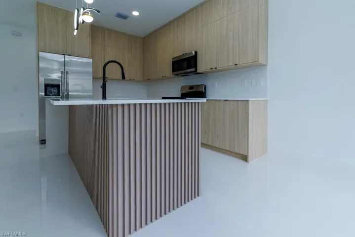 Kitchen with light brown cabinets, light countertops, modern cabinets, and stainless steel appliances