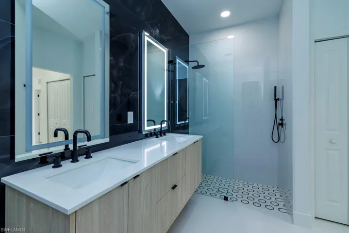 Full bathroom featuring double vanity, a walk in shower, and a sink