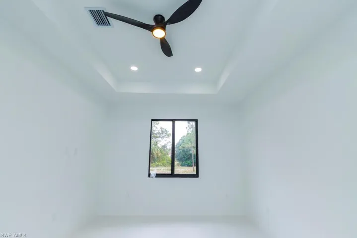 Spare room featuring a tray ceiling, recessed lighting, baseboards, visible vents, and a ceiling fan