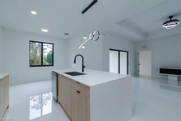 Kitchen with open floor plan, stainless steel dishwasher, a sink, modern cabinets, and light brown cabinets