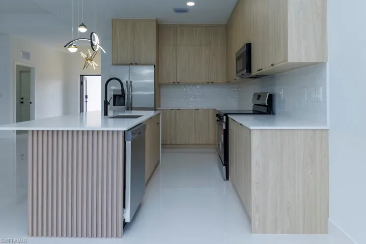 Kitchen with visible vents, modern cabinets, appliances with stainless steel finishes, light brown cabinets, and a sink