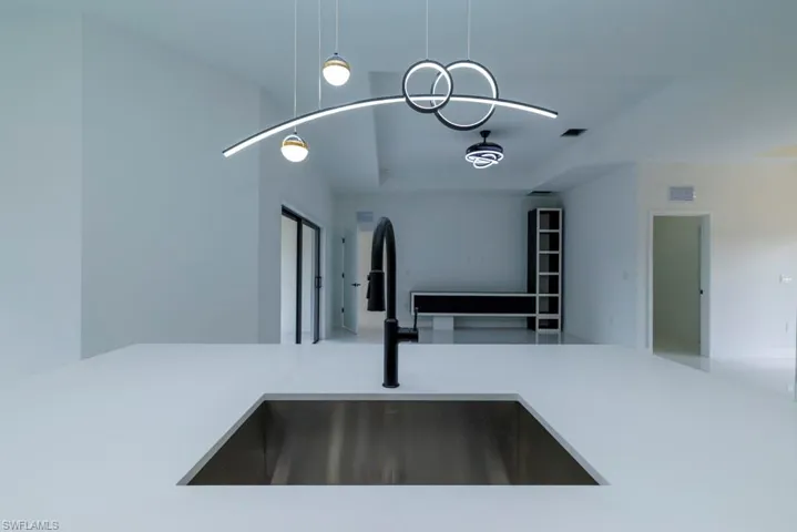 Room details with visible vents, light countertops, a sink, and a raised ceiling