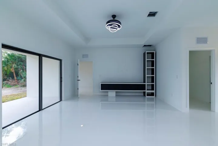 Empty room with a raised ceiling, tile patterned flooring, and visible vents