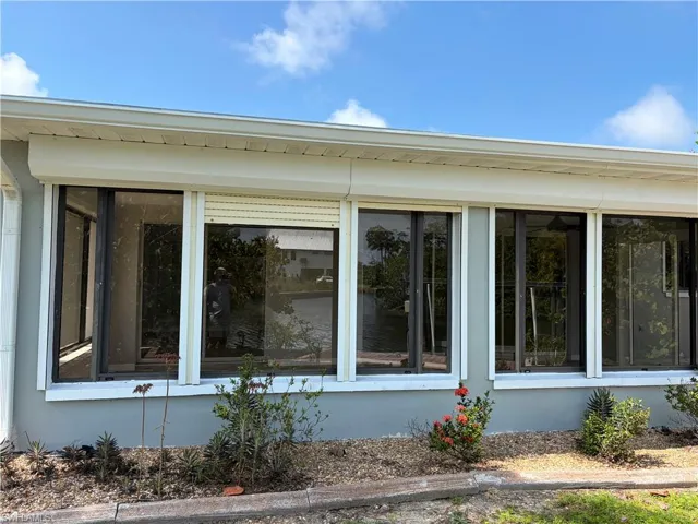 Expansive window wall featuring multiple sliding glass doors, exterior roller shutters, and a direct water view