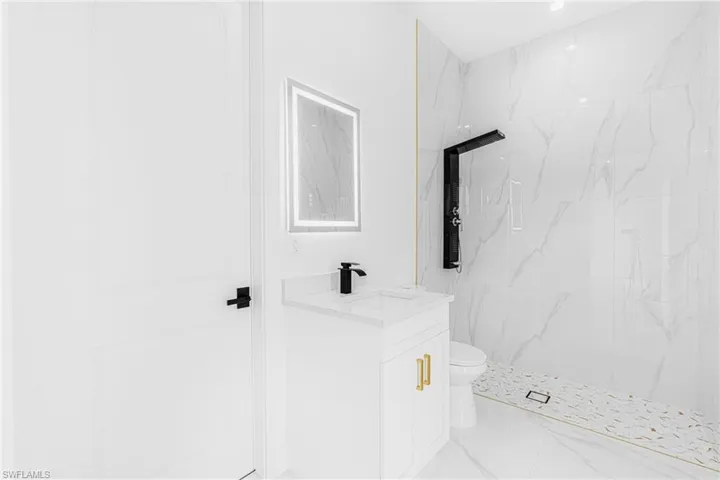 Bathroom featuring vanity, a tile shower, and toilet