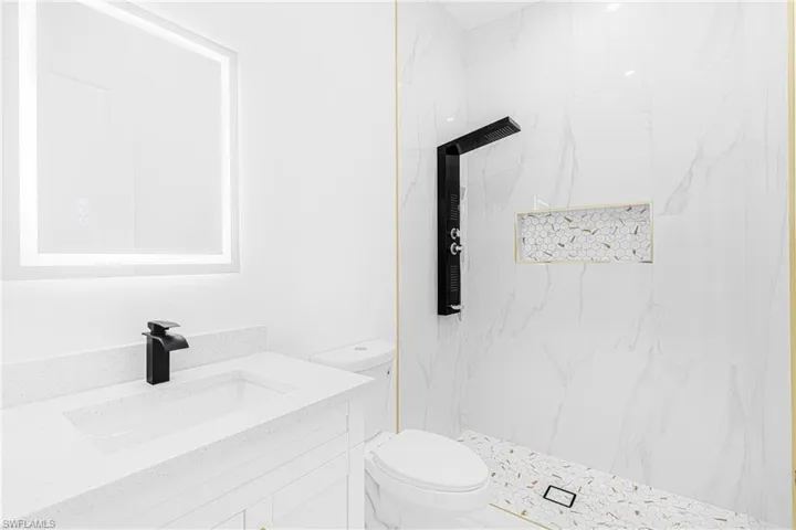 Bathroom featuring vanity, toilet, and tiled shower