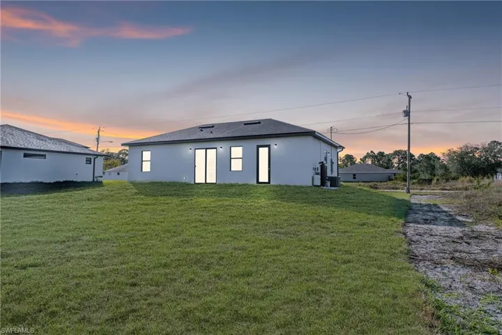 Back house at dusk featuring a lawn