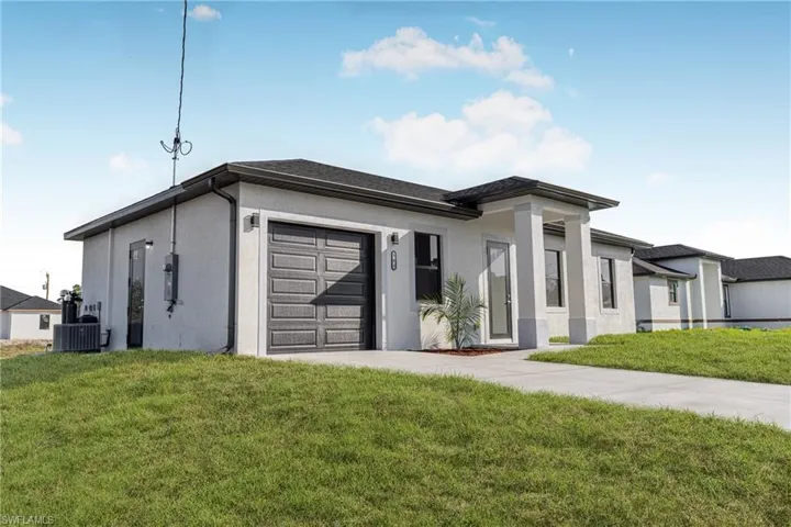 View of front of home with a garage, a front yard, and central air condition unit