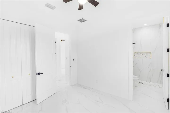 Bathroom featuring ceiling fan, tiled shower, and toilet