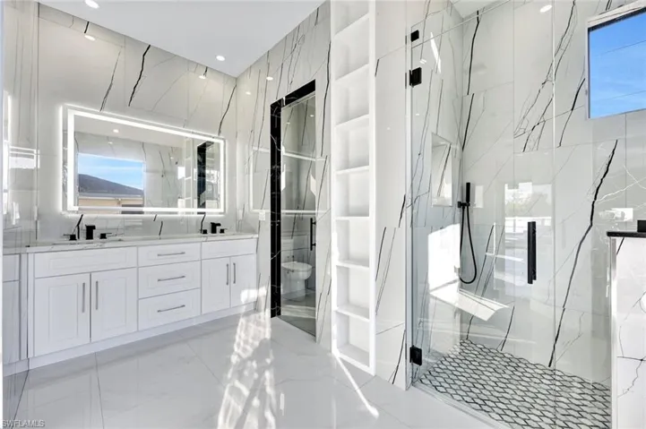 Bathroom featuring double vanity, a marble finish shower, and built in shelves