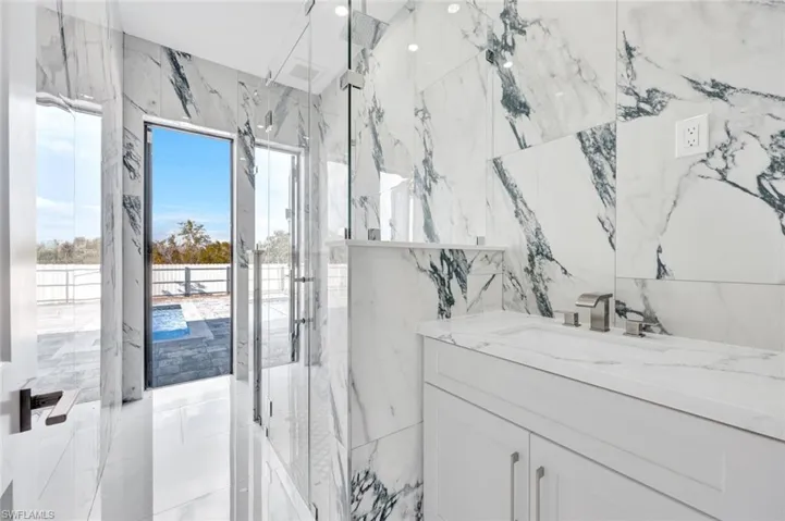 Bathroom with vanity, a marble finish shower, and stone wall