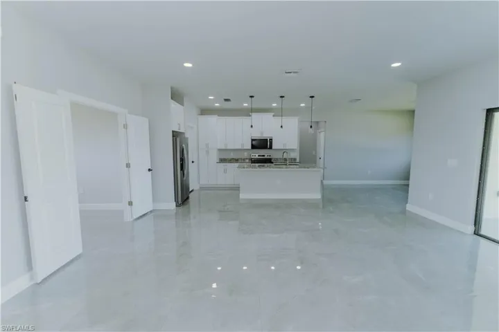 Kitchen with recessed lighting, open floor plan, white cabinetry, appliances with stainless steel finishes, and a sink