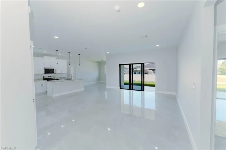 Unfurnished living room with a sink, visible vents, baseboards, and recessed lighting