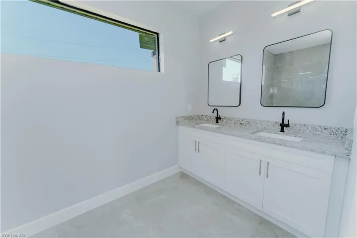 Bathroom featuring a sink, baseboards, and a healthy amount of sunlight