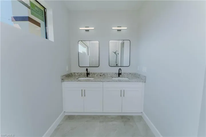 Bathroom with marble finish floor, baseboards, and a sink