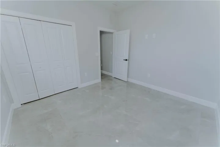 Unfurnished bedroom with a closet, baseboards, and marble finish floor