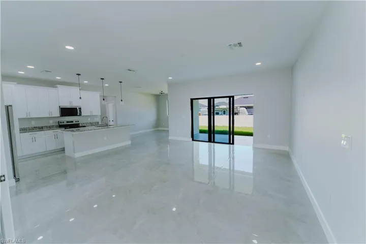 Unfurnished living room featuring a sink, baseboards, visible vents, and recessed lighting