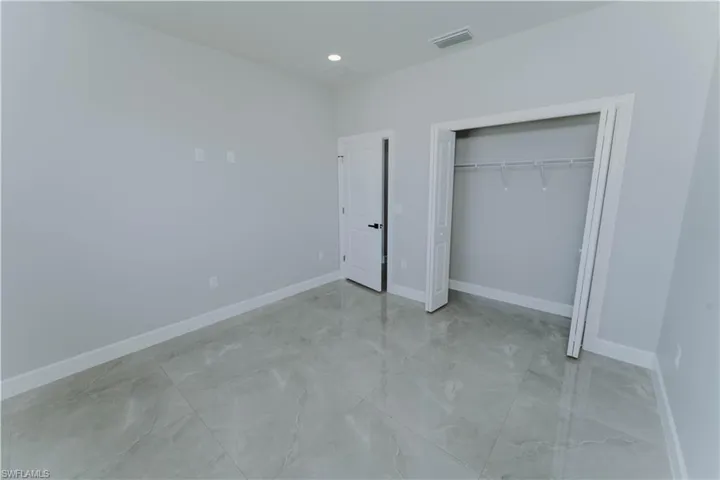 Unfurnished bedroom with a closet, marble finish floor, baseboards, and visible vents